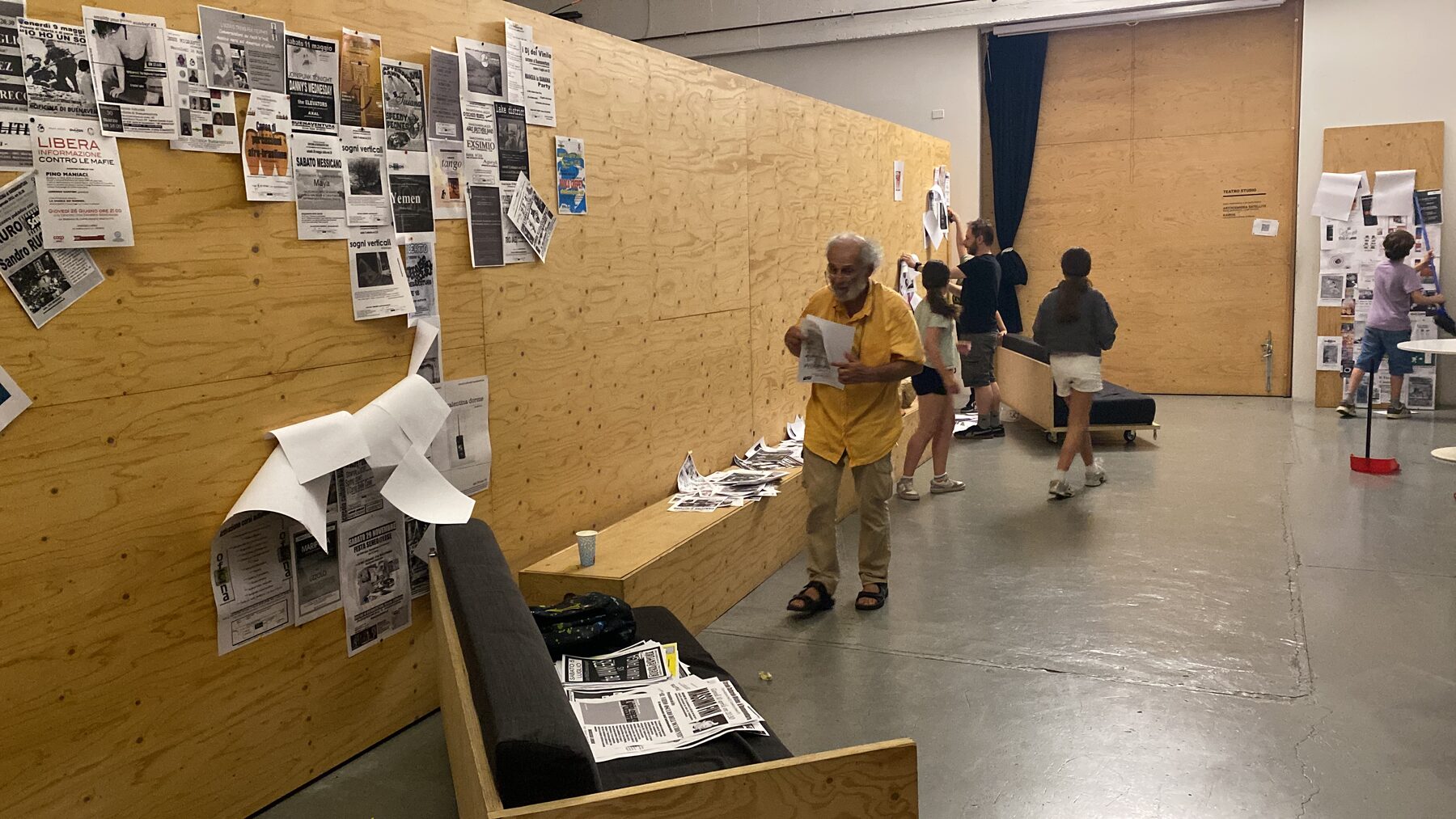 Spazio Zephiro durante il chill della sera: vecchi poster e flyer del Buena 1.0 appesi alle pareti di compensato, gente che cammina, legge, si saluta