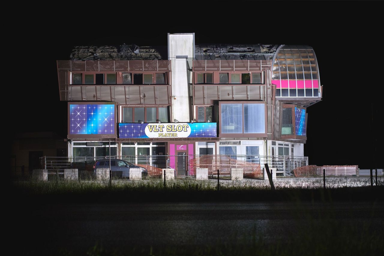 Lo stesso edificio nel 2026: tetto crollato, slot machine al piano terra, insegna 'VLT SLOT PLAYER'