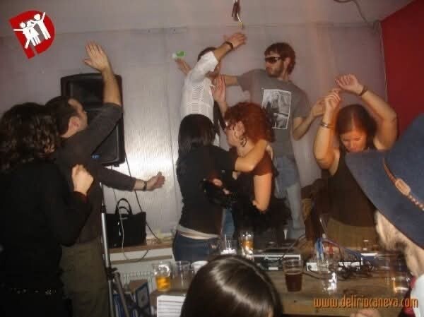 Festa al Buena: ragazza al microfono e gente che balla con le braccia alzate, atmosfera concerto/party.